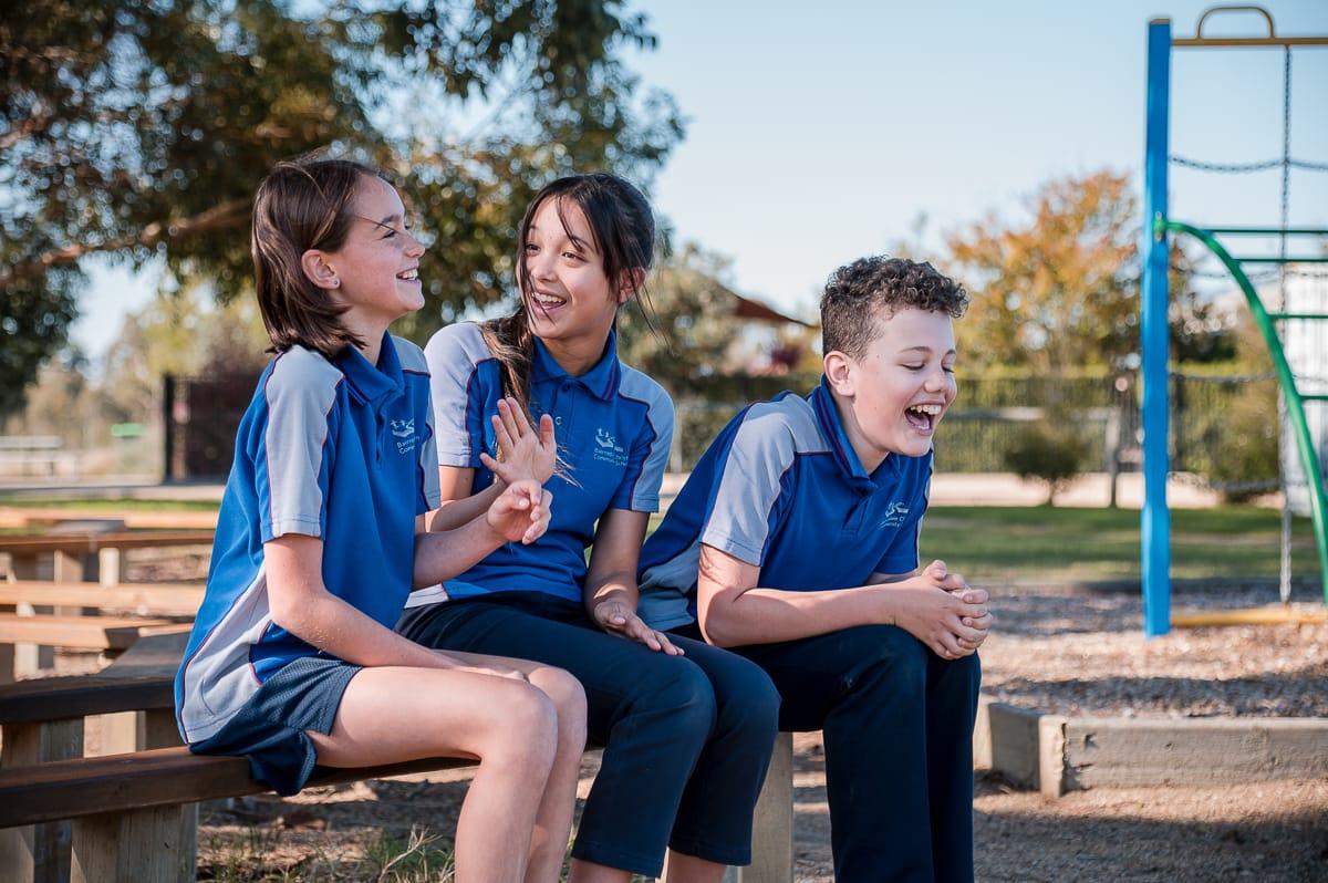 Three upper primary students laughing together outdoors, reflecting the joy, friendship, and personal connection nurtured in a Christ-centred school community.