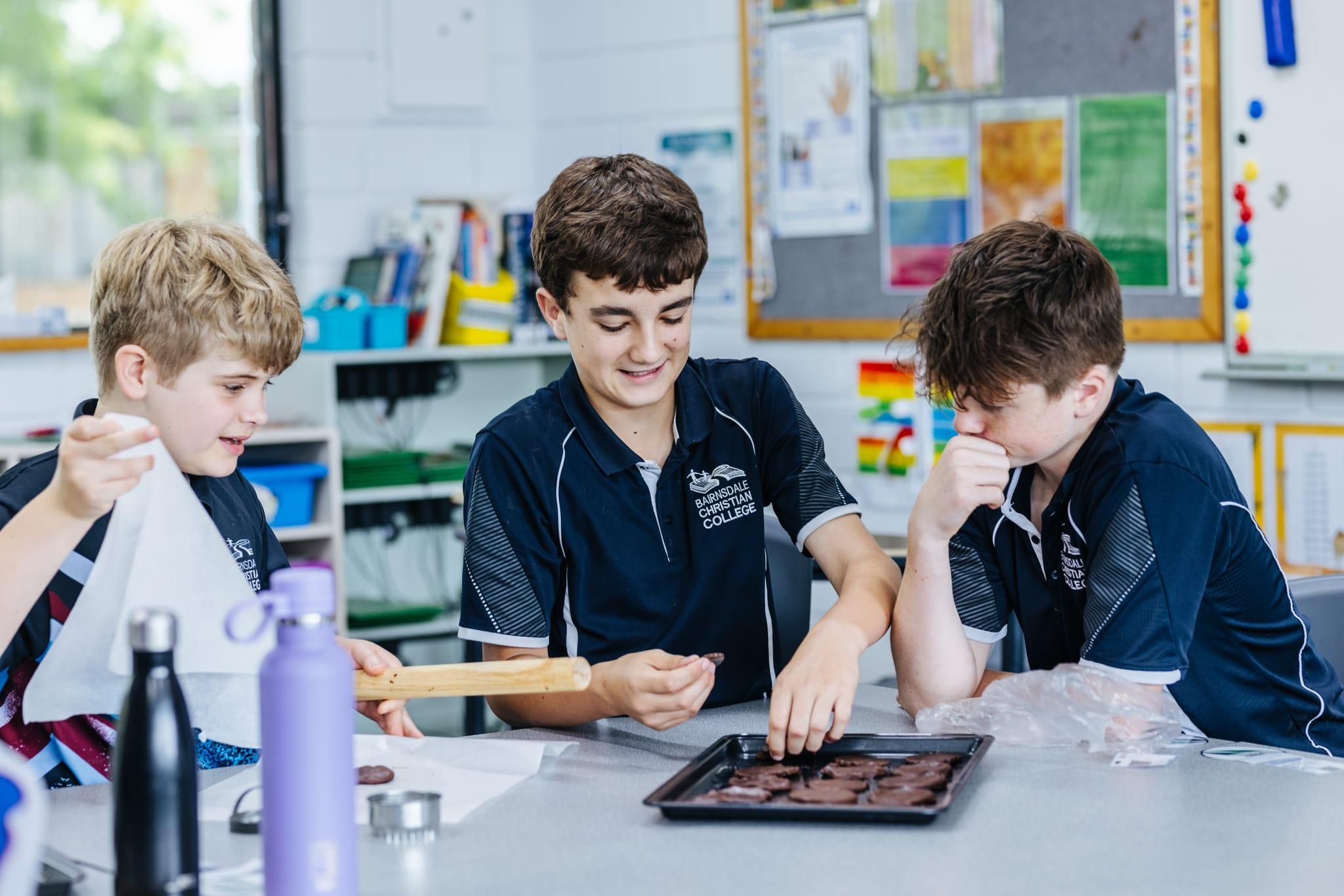 Three year 8 boys participating in a hands-on cooking activity at Bairnsdale Christian College, showcasing teamwork, creativity, and practical learning in a supportive Christian classroom.