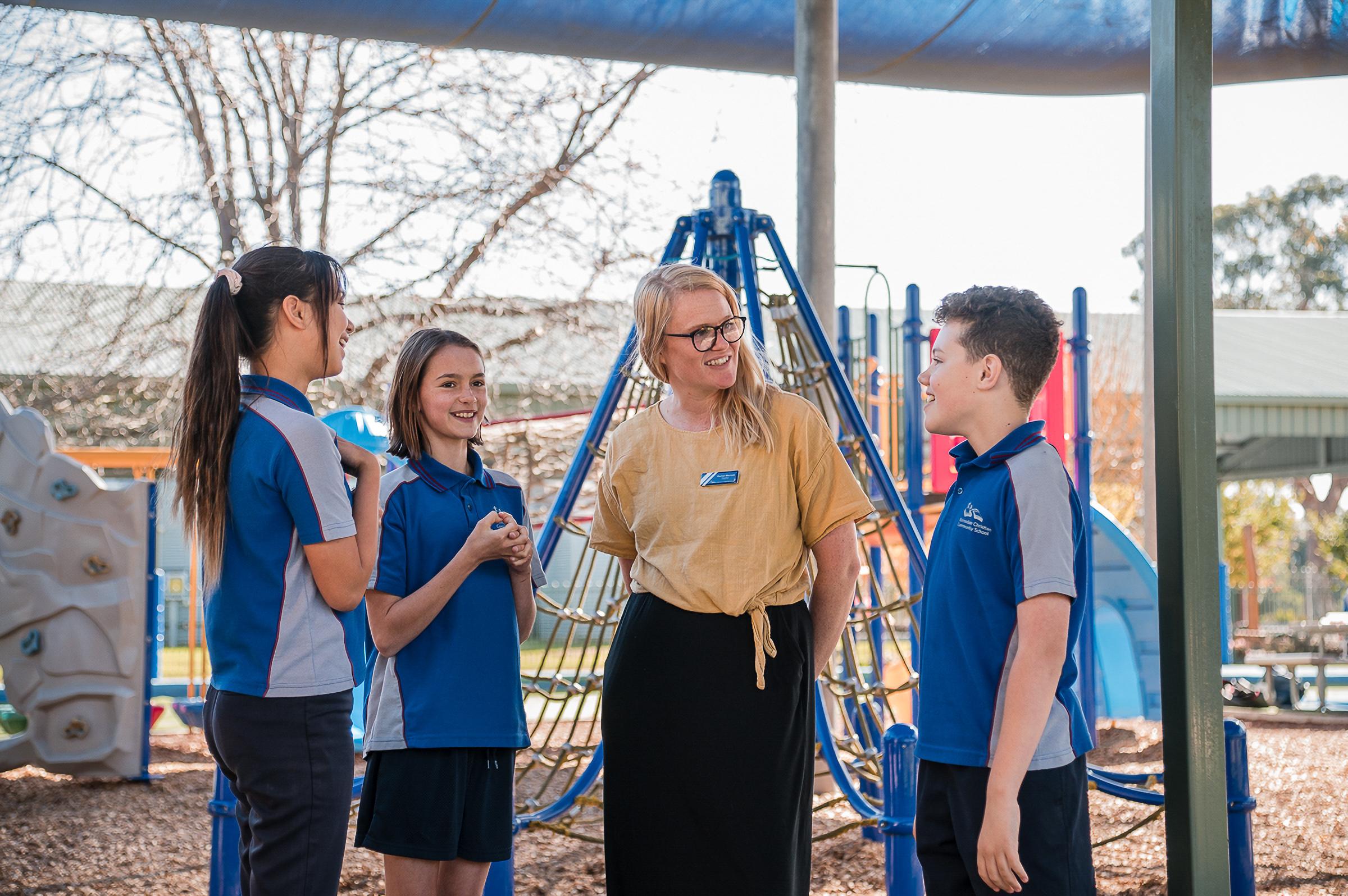 Teacher warmly engaging with primary students in the playground, illustrating the personalised care and strong relationships at the heart of Bairnsdale Christian College’s “Well Known” commitment.