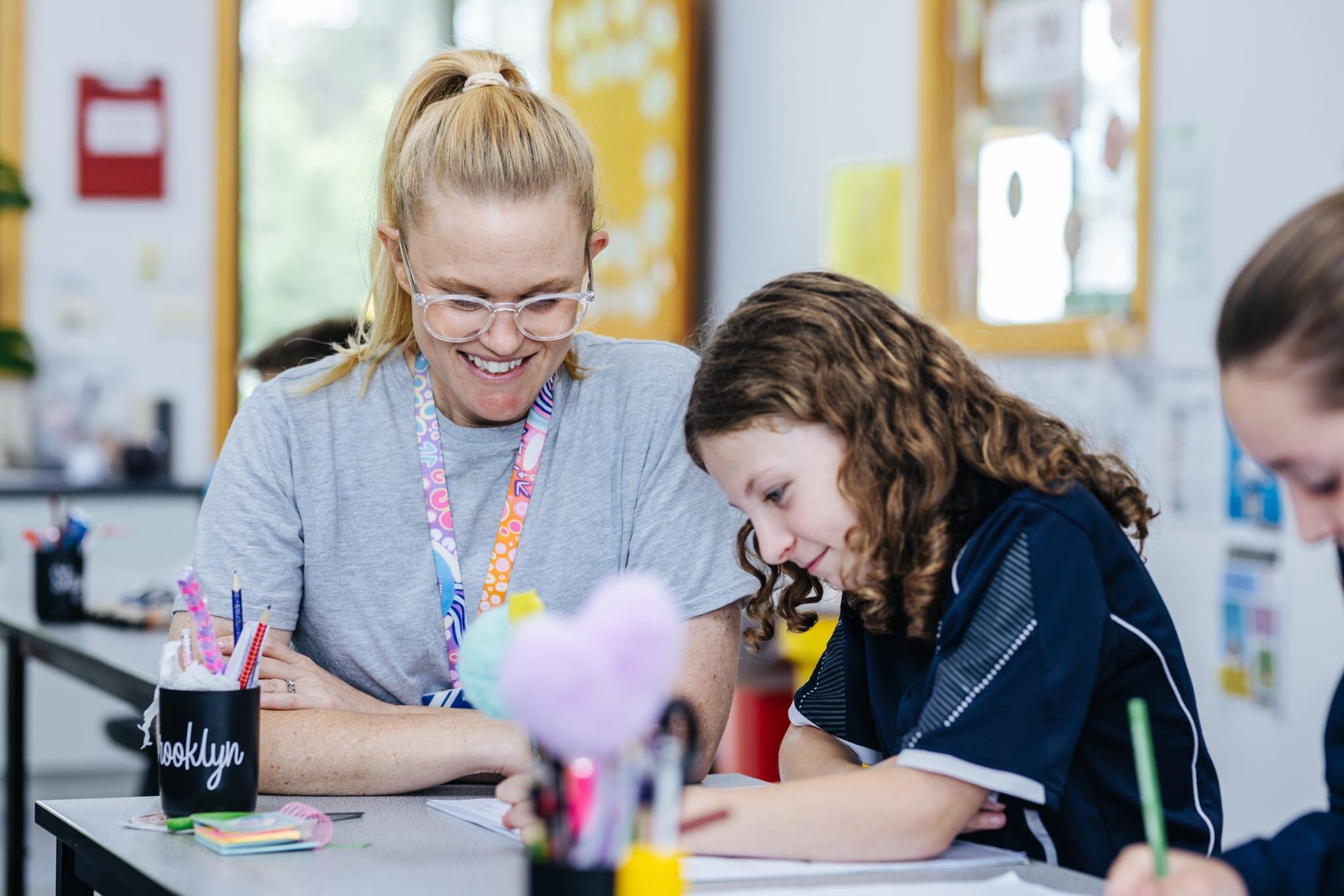 Teacher encouraging a young student during a classroom activity, illustrating personalised support, joy in learning, and the commitment to excellent Christian education at Bairnsdale Christian College.