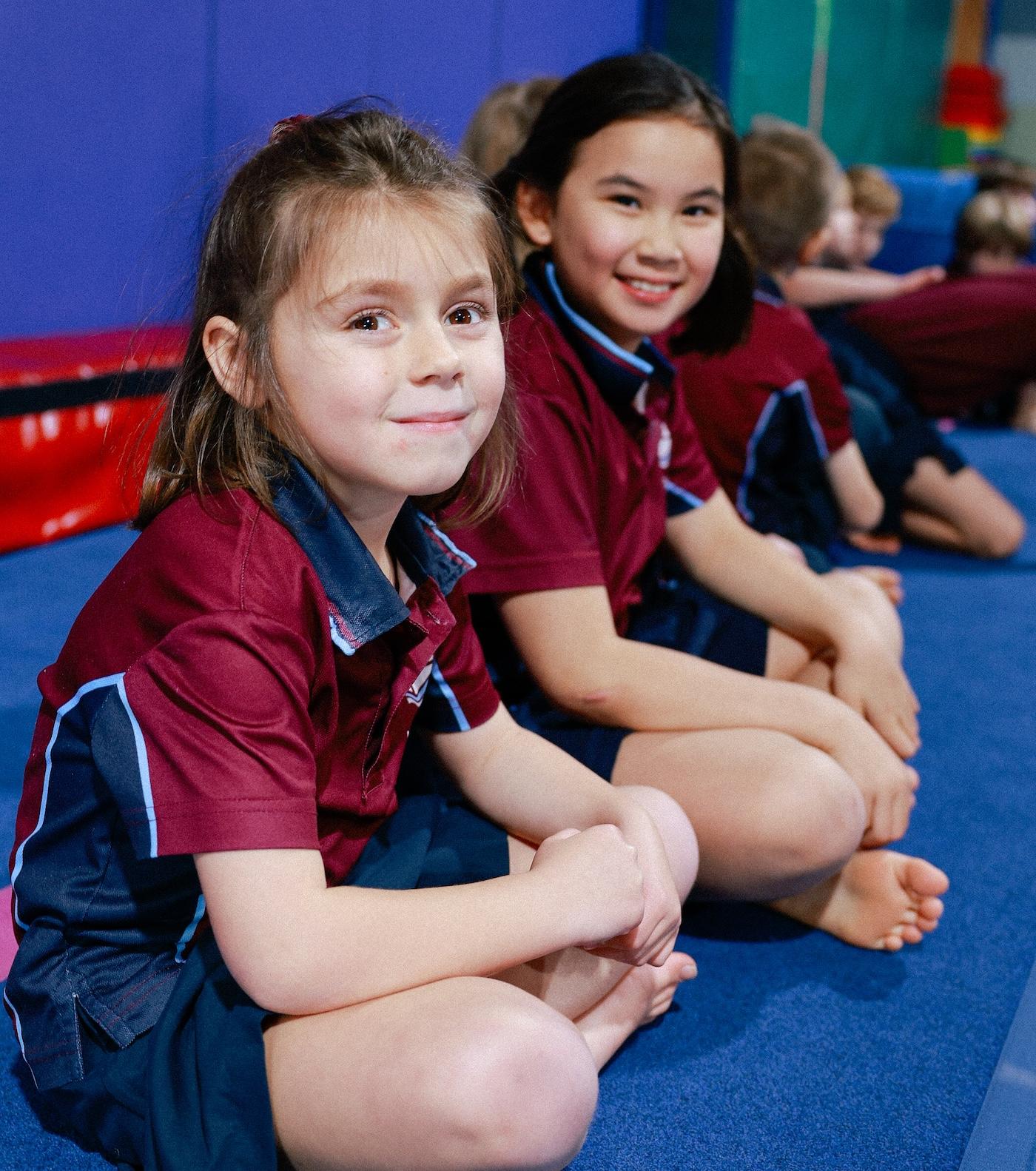 Primary school girls in sitting in gymnastics sports class