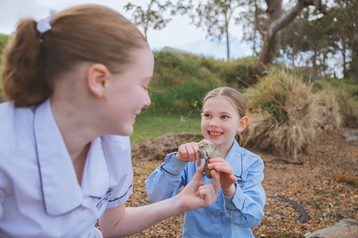Three different female primary school students who are outside, hugging, and smiling