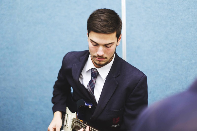 male student concentrating playing guitar